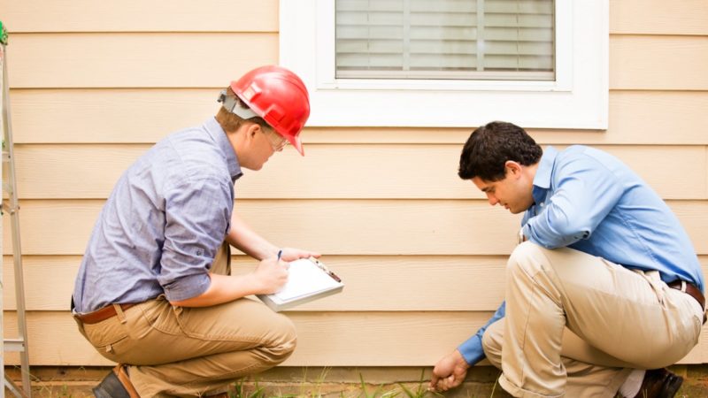 Home inspection: inspector shows prospective buyer something going on where the wall meets the ground outside the house